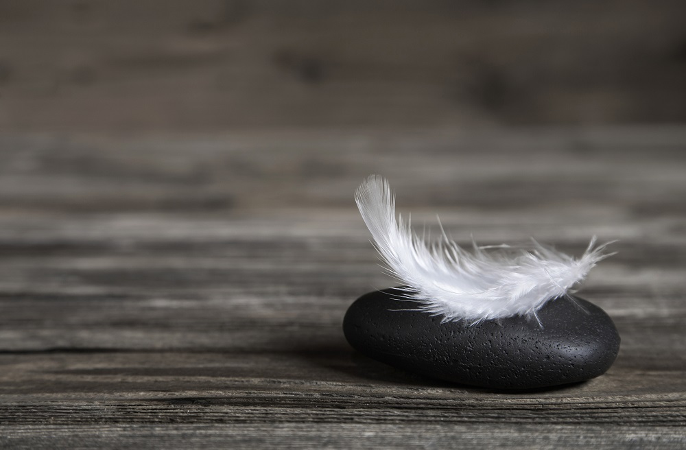 White feather on a black stone condolence ecard.